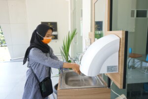 Foto perempuan sedang mencuci tangan sebelum memasuki gedung [Doc. BP2M]