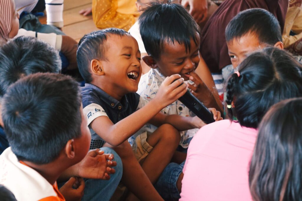 Ekspresi keceriaan terpancar di wajah anak-anak ketika mereka dilibatkan dalam kegiatan "Diuber Segoro" pada Minggu (4/6). Anak-anak di Dukuh Timbulsloko diajak berpartisipasi melalui aktivitas bernyanyi, menggambar, dan menulis. [BP2M/Rifky]