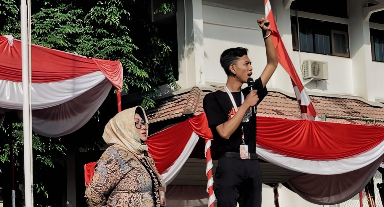 Presiden Mahasiswa BEM KM Unnes, Baharudin Wahyu Aji Dwi Sajiwo, dihampiri oleh ketua panitia dari unsur dosen saat memberikan sambutan dan orasinya pada pembukaan PKKMB Unnes 2024 di Lapangan Prof. Dumadi, Jum'at (16/8). [Dok. Intan Maghfiroh, Mahasiswi Unnes]