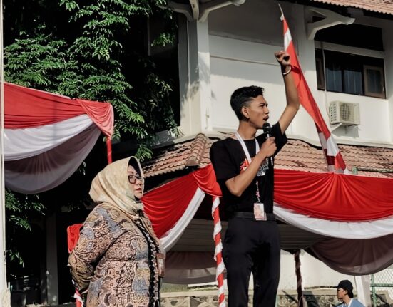 Presiden Mahasiswa BEM KM Unnes, Baharudin Wahyu Aji Dwi Sajiwo, dihampiri oleh ketua panitia dari unsur dosen saat memberikan sambutan dan orasinya pada pembukaan PKKMB Unnes 2024 di Lapangan Prof. Dumadi, Jum'at (16/8). [Dok. Intan Maghfiroh, Mahasiswi Unnes]