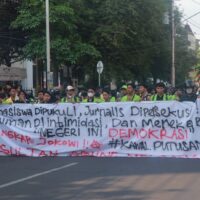 Spanduk sindiran terhadap penyelewengan demokrasi dan represifitas polisi dibentangkan dalam perjalanan menuju titik aksi, Senin (26/08). [BP2M/Anastasia]