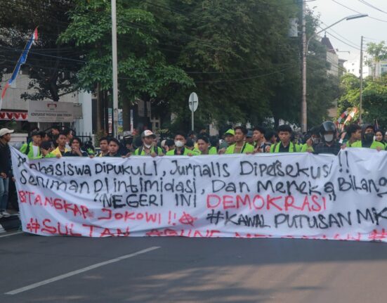 Spanduk sindiran terhadap penyelewengan demokrasi dan represifitas polisi dibentangkan dalam perjalanan menuju titik aksi, Senin (26/08). [BP2M/Anastasia]