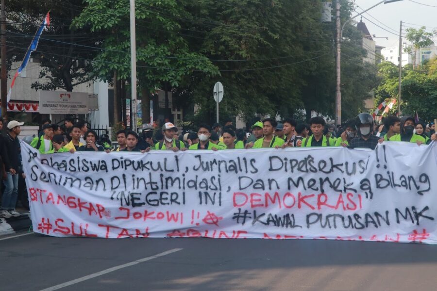 Spanduk sindiran terhadap penyelewengan demokrasi dan represifitas polisi dibentangkan dalam perjalanan menuju titik aksi, Senin (26/08). [BP2M/Anastasia]