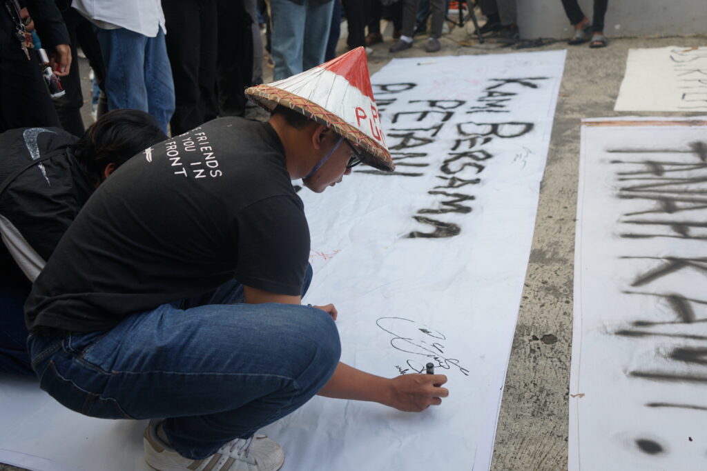 Seorang yang mengikuti aksi turut serta menandatangani petisi yang dibuat bersama masyarakat sipil yang bersolidaritas bersama Petani Desa Pundenrejo. (Senin, 28/04/2025) [Lidwina/BP2M]