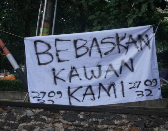 Sepotong spanduk terbentang di Taman Simpang Tujuh bertuliskan “Bebaskan Kawan Kami”. (Kamis, 22/05/2025) [Sultan/Magang BP2M]