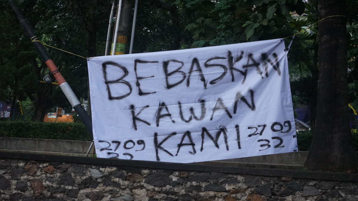 Sepotong spanduk terbentang di Taman Simpang Tujuh bertuliskan “Bebaskan Kawan Kami”. (Kamis, 22/05/2025) [Sultan/Magang BP2M]