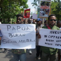 Dua orang bersama dengan massa aksi yang lain tengah membentangkan karton bertuliskan “Papua bukan sarang militer” dan “Hukum diciptakan bukan untuk Orang Papua”. (Rabu, 28/05/2025) [Lidwina/BP2M]