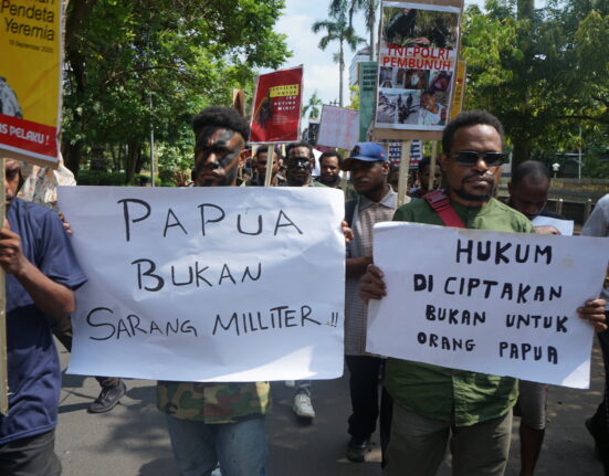 Dua orang bersama dengan massa aksi yang lain tengah membentangkan karton bertuliskan “Papua bukan sarang militer” dan “Hukum diciptakan bukan untuk Orang Papua”. (Rabu, 28/05/2025) [Lidwina/BP2M]