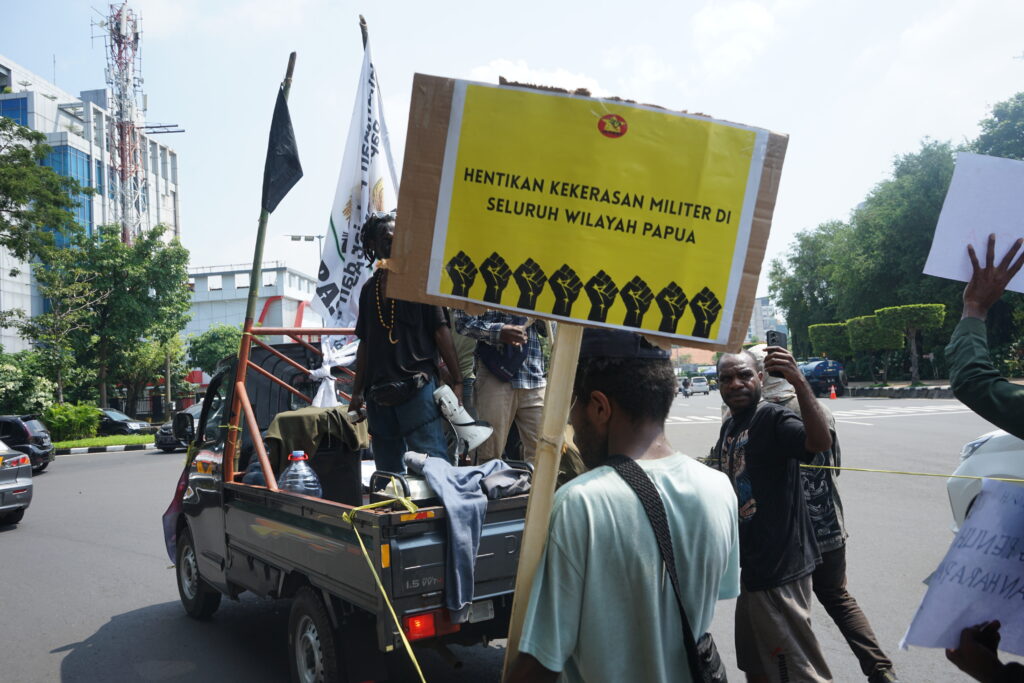 Seorang massa aksi membawa poster bertuliskan “Hentikan kekerasan militer di seluruh wilayah Papua” di belakang mobil komando. (Rabu, 28/05/2025) [Lidwina/BP2M]
