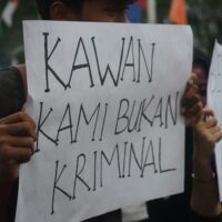 Seorang mahasiswa membentangkan kertas seruan yang bertuliskan “Kawan Kami Bukan Kriminal”. (Rabu, 21/05/25) [Ann/Magang BP2M]