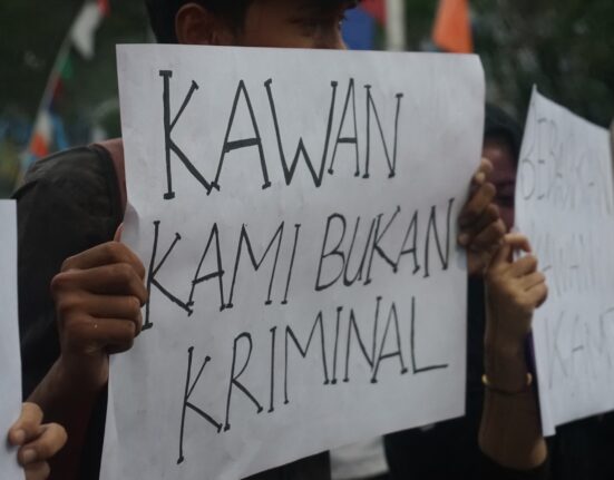 Seorang mahasiswa membentangkan kertas seruan yang bertuliskan “Kawan Kami Bukan Kriminal”. (Rabu, 21/05/25) [Ann/Magang BP2M]