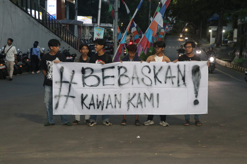 Mahasiswa Universitas Negeri Semarang (Unnes) memegang spanduk yang bertulisan “Bebaskan Kawan Kami” di Simpang Tujuh Unnes. (Kamis, 19/07/2025) [Sultan/Magang BP2M]
