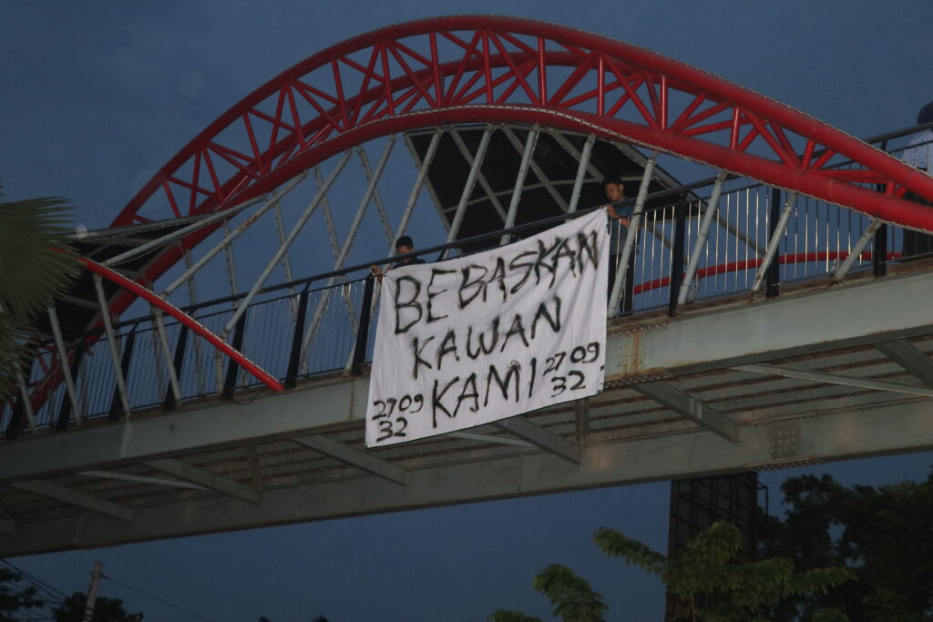 Selembar spanduk yang tergantung di jembatan sekitar Simpang Tujuh Unnes bertuliskan “Bebaskan Kawan Kami”. (Kamis, 19/07/2025) [Lidwina/BP2M]