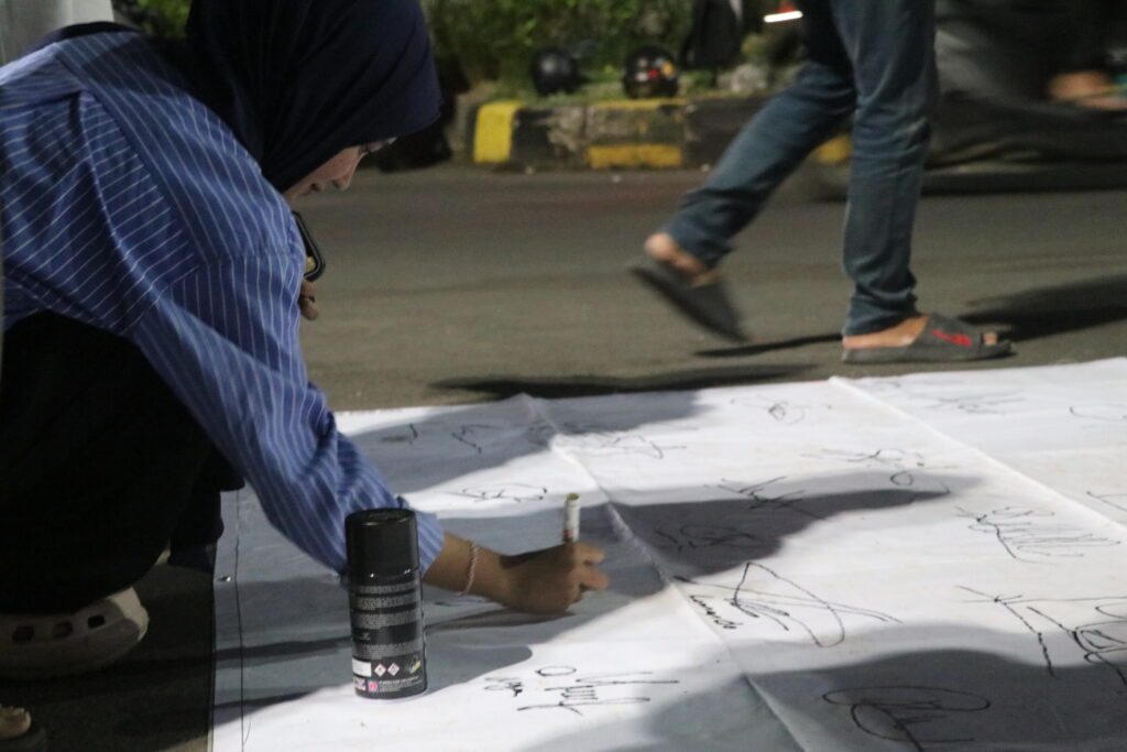 Seorang perempuan dalam aksi turut serta menandatangani petisi yang dibuat oleh SOMASI sebagai wujud solidaritas. (Kamis,19/07/25) [Sultan/Magang BP2M]