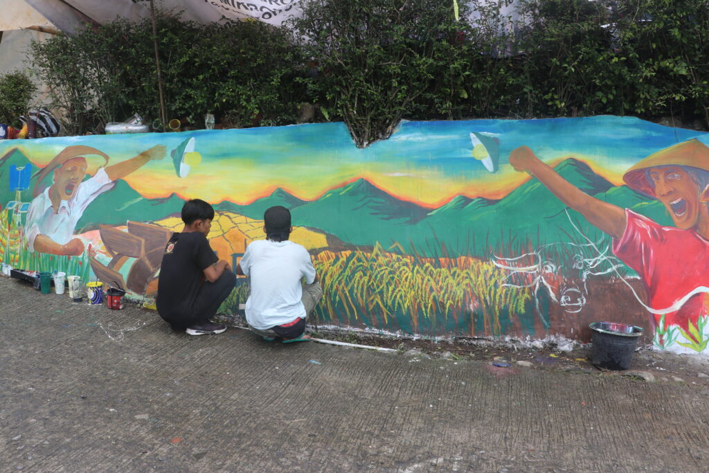 Mural dari komunitas seni Corong Api bersama dua orang pelukisnya (Sabtu, 25/20/2025)